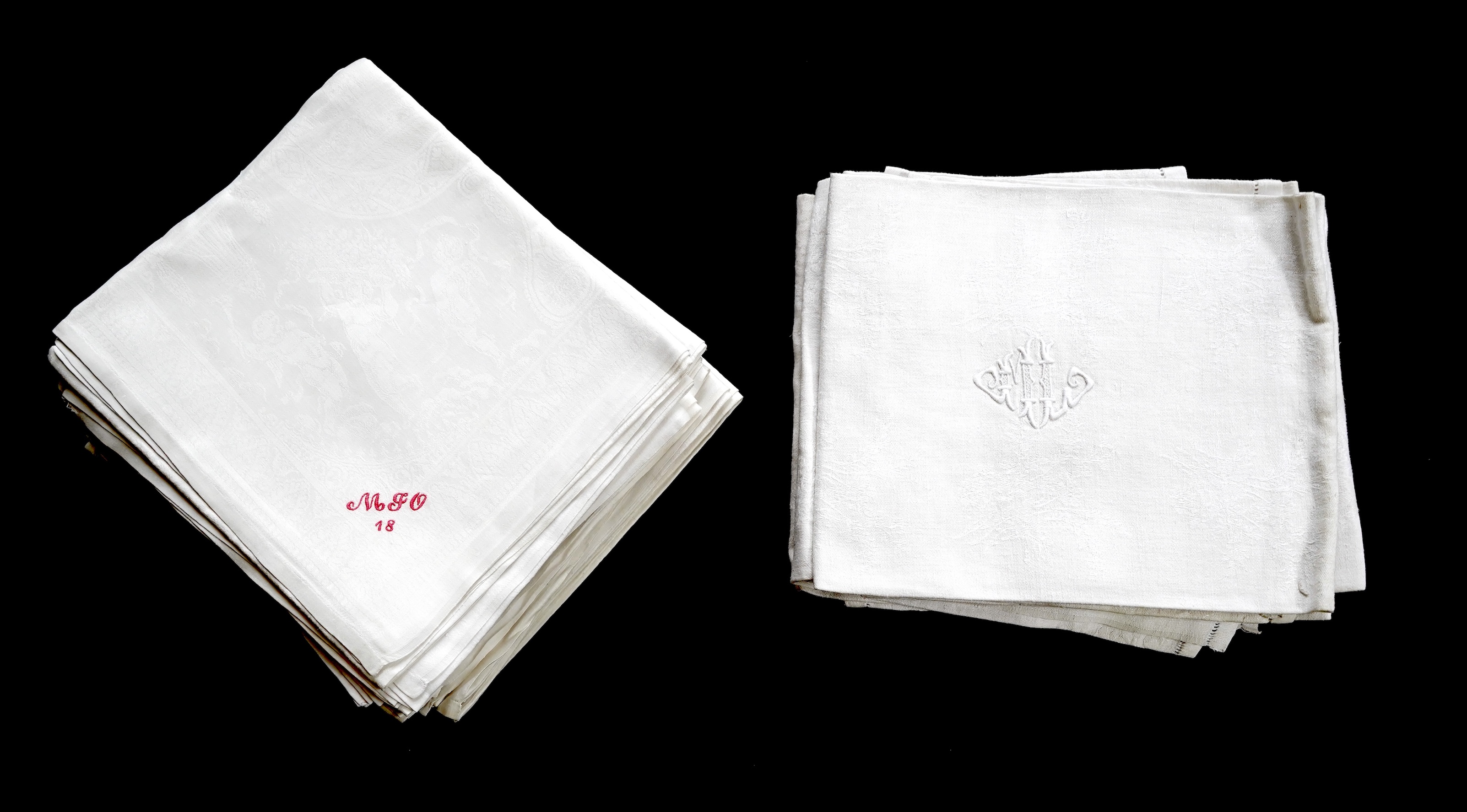 A set of nine red monogrammed 19th century large damask dinner napkins and a similar set of coarser French provincial damask napkins, the large set, decoratively designed with a boating river scene, amongst classical bui